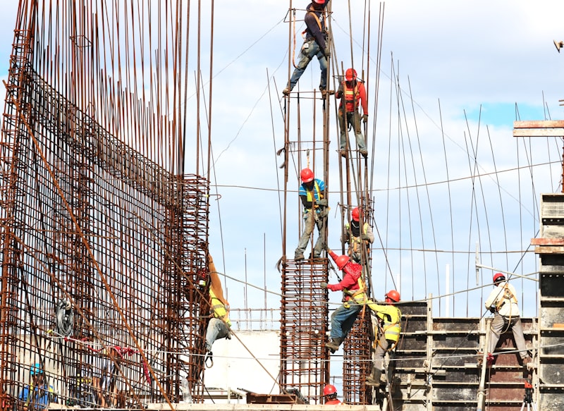 Construction workers with safety harnesses building a commercial rebar structure