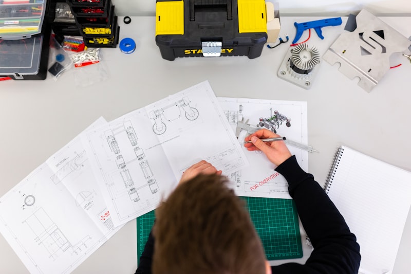 Engineer measuring technical construction drawings and blueprints at a planning desk